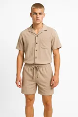 Camisa de lino color crudo, de manga corta, con cuello camisero y bolsillo de parche en el pecho.