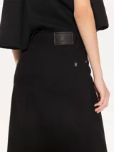 Pollera larga negra de tejido camisero liviano, con recortes verticales y diagonales que generan movimiento.