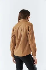 Sobrecamisa color marrón de poliuretano, con cuello clásico, cierre frontal con botones a presión, mangas largas con puños abotonados, dos bolsillos tipo parche con solapa y botón en el pecho.