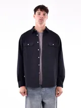 Camisa negra de corte clásico, con dos bolsillos en el pecho y cierre frontal de botones.