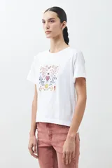 Remera blanca de algodón con cuello redondo y mangas cortas. Estampado rectangular con diseño floral y geométrico en tonos rojos, azules y amarillos.