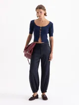 Top corto gris de punto acanalado, con escote redondo, manga corta abullonada y cierre frontal con tres ganchos decorados con piedras.