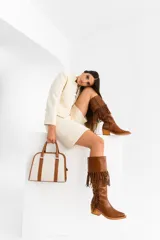 Bota tejana de caña alta color negro, confeccionada 100% en cuero vacuno. Presenta taco de madera foliado en cuero, cierre YKK del lado interior y flecos colocados a mano en la caña.