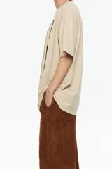 Camiseta de algodón orgánico color beige, corte oversize y manga corta ancha. Presenta un estampado central enmarcado con motivos florales y el texto "BIMBA Y LOLA" en la parte superior e inferior del diseño.