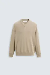 Jersey de punto color beige, con cuello en V y mangas largas.