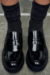 Mocasín negro de charol con detalle de antifaz en el empeine y punta redonda.
