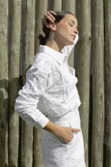 Camisa blanca con textura de encaje, de corte recto, manga larga y cuello camisero.