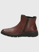 Botín de cuero color marrón con paneles elásticos laterales negros, diseño tipo Chelsea y suela de goma flexible negra con costuras decorativas visibles.