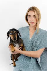 Ruana celeste tejida a mano en cinta de lana merino, con flecos en el borde inferior.