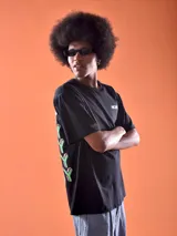 Remera negra de corte oversized con estampado pequeño en el pecho con la palabra "Mickey" en color verde.