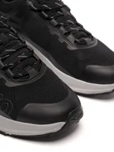 Championes Umbro modelo Adventure para hombre, color negro con detalles en gris oscuro. Presentan una capellada de malla transpirable con refuerzos sintéticos y la marca Umbro en relieve sobre el lateral. La suela es gruesa, de color gris claro, con una base negra.