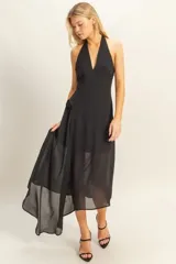 Vestido negro de largo midi, con escote halter y falda asimétrica con caída fluida.