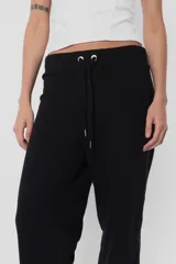 Pantalón de jogging color beige, de frisa y corte relajado. Con cintura de rib al tono, cordones con punteras metálicas y ojalillos personalizados de marca. Detalle de bordado a contratono en ambos laterales de pierna.