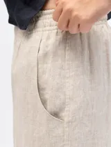 Pantalón de lino beige de corte holgado, con cintura elástica, dos bolsillos laterales y un bolsillo trasero.