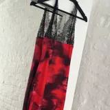 Vestido largo de tirantes finos con encaje negro en el escote y estampado abstracto en tonos rojos y negros.