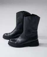 Bota de cuero vacuno color marrón, con caña media, suela de caucho y punta redonda.