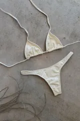 Conjunto de bikini verde esmeralda, con corpiño triangular de atar al cuello y espalda, con almohadillas desmontables, y bombacha colaless con laterales fijos.