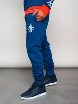 Pantalón de jogging azul con puños ajustados, cintura elástica con cordón y escudo del Club Nacional de Football en la pierna izquierda.