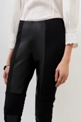 Pantalón negro de corte recto con paneles de cuero sintético en la parte delantera y trasera.