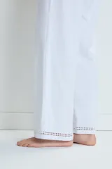 Conjunto de pijama blanco de algodón, compuesto por una remera de mangas cortas con cuello en V y detalle de calado en los bordes, y un pantalón largo de corte recto con calado en el ruedo.