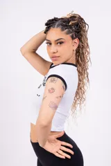 Remera corta de jersey color rosa con cuello redondo y mangas cortas con ribete blanco. Estampado frontal con la inscripción "ST-TROPEZ" en letras blancas.