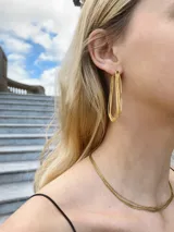 Aros colgantes dorados con forma de lágrima formados por múltiples cadenas finas entrelazadas.
