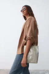 Bolso mini tipo shopper color dorado, con cordón ajustable y correa larga.