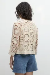 Chaqueta corta color beige, tejida a crochet con diseño floral.