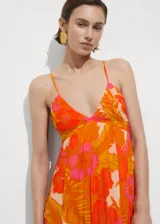 Vestido largo con estampado floral en tonos naranja, amarillo y rosa. Tiene tirantes finos, escote en V drapeado y corte evasé.