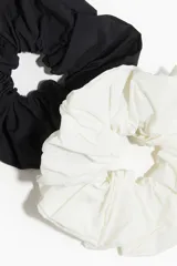 Pack de dos scrunchies elásticos de nylon, uno negro y otro blanco.