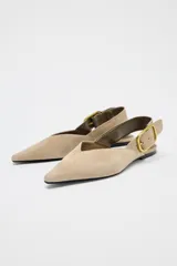 Zapato plano destalonado color beige, de serraje, con punta fina y tira trasera con hebilla metálica.
