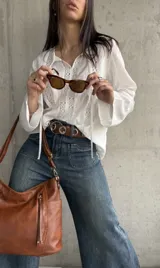 Blusa blanca de manga larga con detalles de encaje en el frente, mangas y cuello.