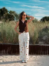 Pantalón de jean color marrón con corte recto, tiro alto y detalle de ojalillos metálicos grandes a lo largo de las piernas.