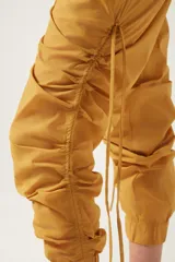 Pantalón jogger negro de nylon con elástico ancho en la cintura, puños elásticos ajustables y lazos laterales para fruncir.