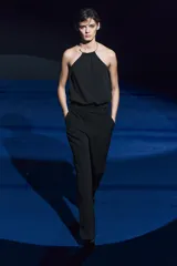 Pantalón negro de tiro medio, con trabillas en la cintura, bolsillos laterales y de vivo en la espalda, raya planchada en el delantero y pierna recta.