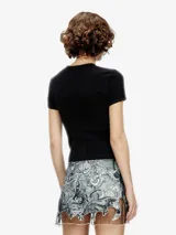 Top negro de manga corta, ajustado al cuerpo, con cuello redondo y costuras expuestas en contraste. Presenta un estampado frontal con el nombre "Diesel" en tipografía gótica rodeado de un diseño tipo explosión o sol radiante en color plateado.