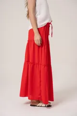 Falda larga roja de gasa con volados y cintura ajustable con cordón.