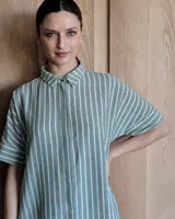 Vestido túnica celeste de lino con rayas verticales blancas, corte recto, cuello camisero y mangas cortas.