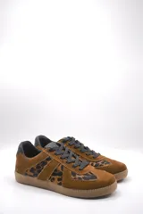 Zapatillas urbanas de cuero color crema con detalles en gris y suela de goma marrón.