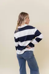 Sweater de manga larga con diseño de rayas anchas horizontales en azul marino y blanco. Posee cuello polo con cartera de botones y calce relajado.