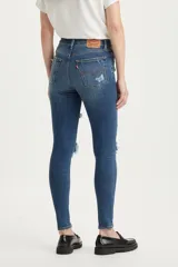 Jean skinny de tiro alto color azul denim con roturas grandes en ambas rodillas y pequeños detalles de roturas en los muslos.