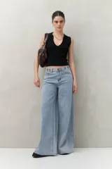 Pantalón de jean negro de corte ultra wide, tiro medio y detalles metálicos en la cintura.