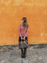 Blusa celeste y blanca a rayas verticales con cuello cuadrado, mangas largas con frunce en los hombros y corte peplum. Cierre frontal con botones. 