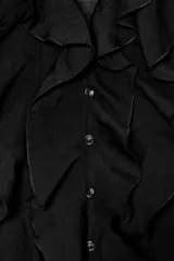 Camisa color rosa pálido confeccionada en tejido ligero con lyocell. Presenta escote en V, cierre frontal con botones, mangas largas abullonadas con puños elásticos y detalle de volantes en el frente.