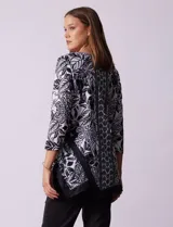 Blusa estampada en blanco y negro con diseño floral, de la marca Ruby Rd. Tiene cuello redondo con apliques de brillos, mangas 3/4 y ruedo asimétrico.