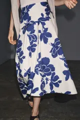 Falda midi de tiro medio confeccionada en hilatura de algodón, color blanco con estampado de flores azules. Cierre lateral con botones.