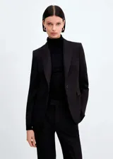 Blazer negro entallado con cuello de pico y solapa con muesca, manga larga, hombros estructurados, dos bolsillos de ribete delanteros, pinzas, abertura posterior y forro interior.