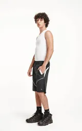 Bermuda negra con recortes blancos, calce oversize de textil liviano, con elástico en la cintura y cordón de ajuste con bolsillos delanteros y traseros.
