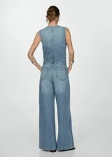 Mono largo de jean celeste con corte wide leg, sin mangas, escote en V, bolsillos de parche en el pecho y laterales, trabillas y cierre frontal con botones.