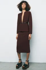 Chaqueta marrón de punto con cuello redondo y manga larga. Incluye cinturón fino negro con hebilla circular.
